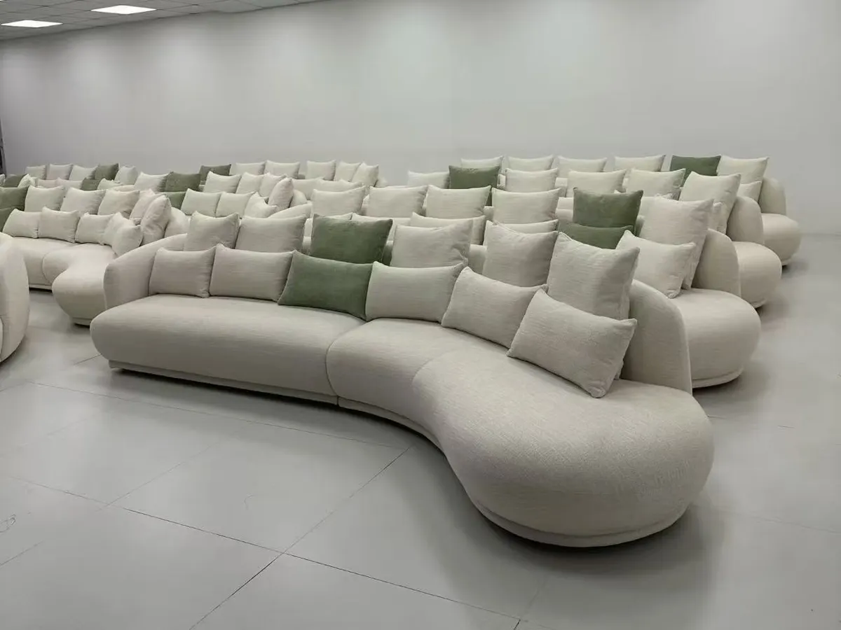 Rows of curved cream upholstered sofas with cushions arranged in a large room